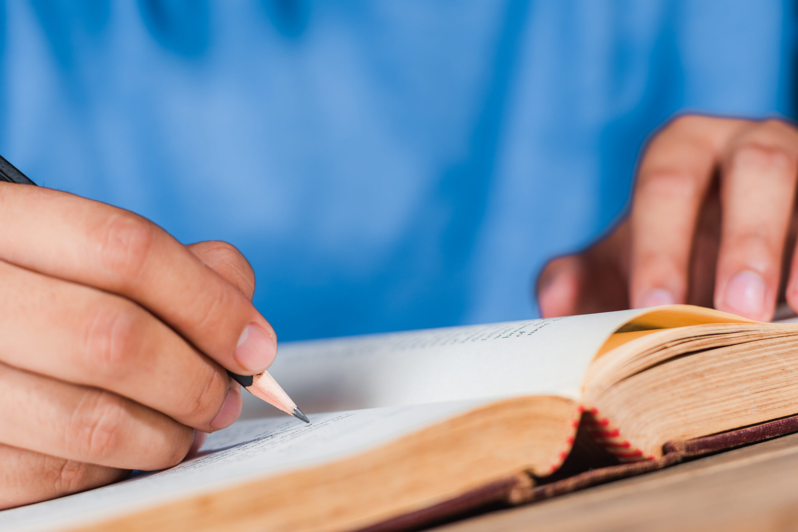 a man writing note with wooden pencil in old book
